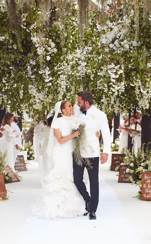 Jennifer Lopez and Ben Affleck walking the aisle at their Georgia wedding, with JLo in a Ralph Lauren high-neck ruffle mermaid gown beneath a canopy of white flowers and hanging moss