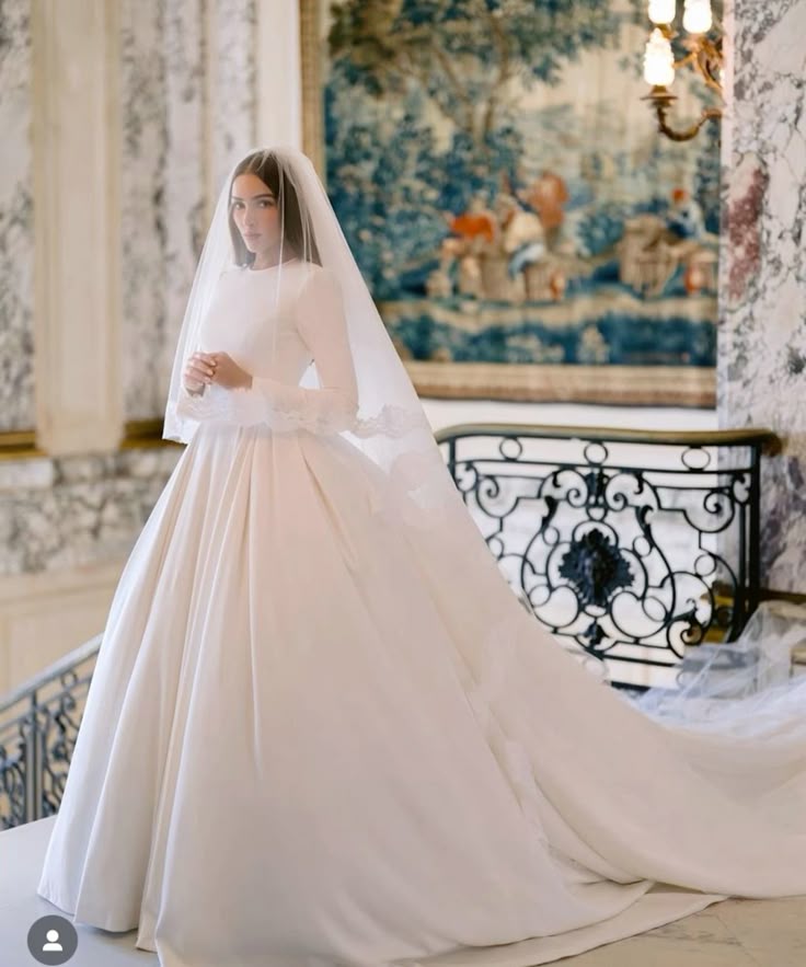 Olivia Culpo in her custom Chanel wedding dress featuring a long-sleeve satin ball gown with cathedral veil in a grand French château