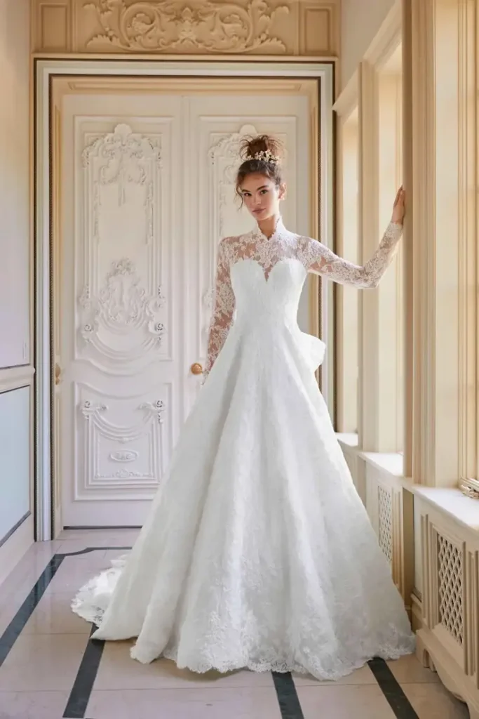 Lace A-line wedding gown with a sheer high neckline and long lace sleeves in an ornate European interior at La Mariée Boutique Tulsa