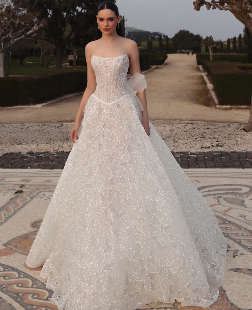 Strapless floral jacquard ball gown wedding dress with a sheer corset bodice and organza bow detail at La Mariée Boutique Tulsa
