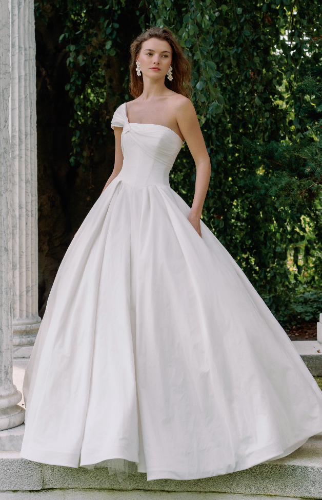 One-shoulder twisted knot satin ball gown wedding dress with a ruched bodice and full pleated skirt at La Mariée Boutique Tulsa