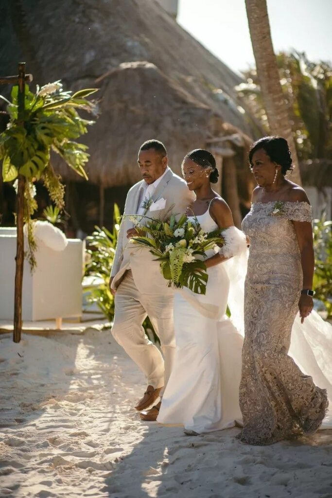 Mother and father walking bride down the aisle during a seaside ceremony