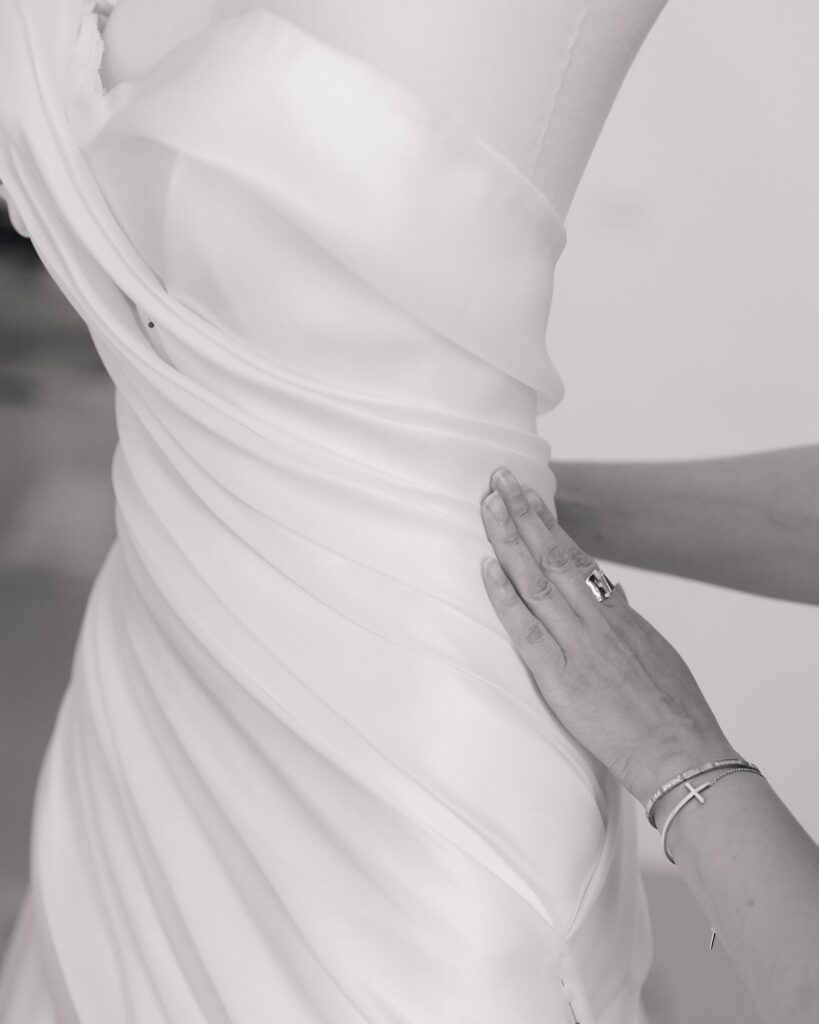 A seamstress working on a dress bodice on a mannequin inside of a bridal atelier