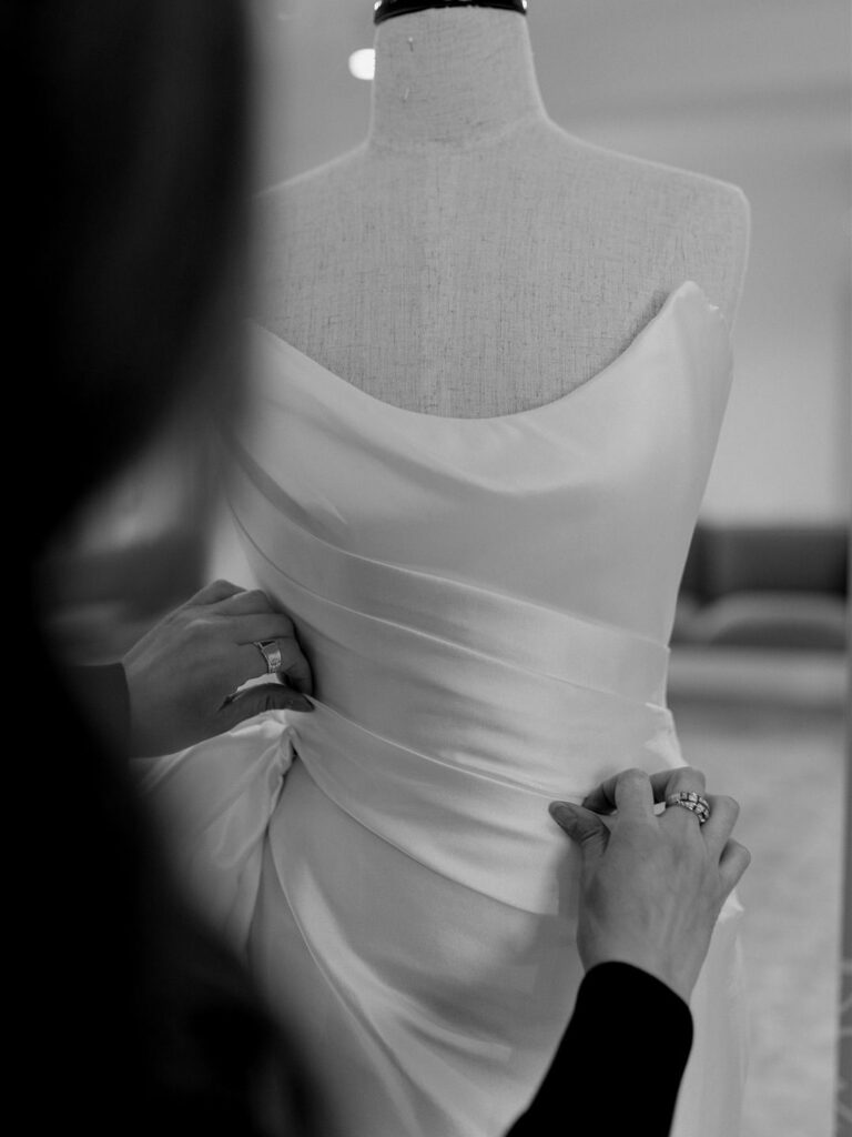 A seamstress pinning a dress inside a bridal atelier